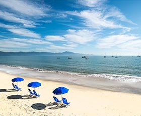 Cadeiras e guarda sóis na área de areia da praia de Jurerê em Florianópolis, Santa Catarina